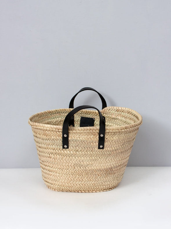 Basket bag with short black leather handles.