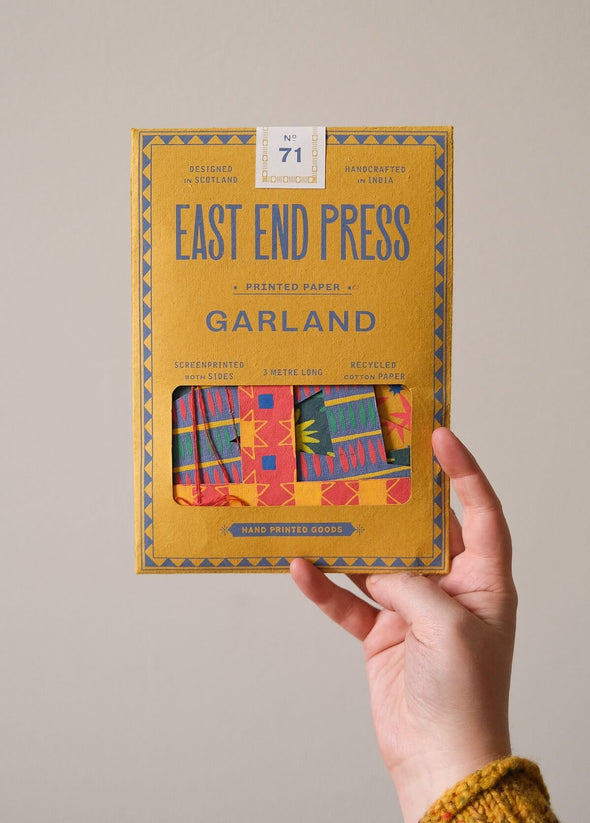 Hand holding the packaging of a Happy Birthday banner 