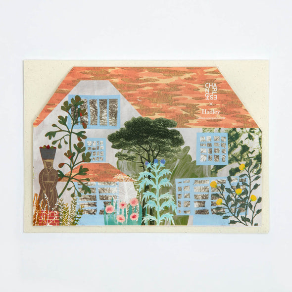 Greetings card in the shape of a house. It has sky blue window frames and a red tiled roof. Lots of flowers and greenery grow infront and up the walls.