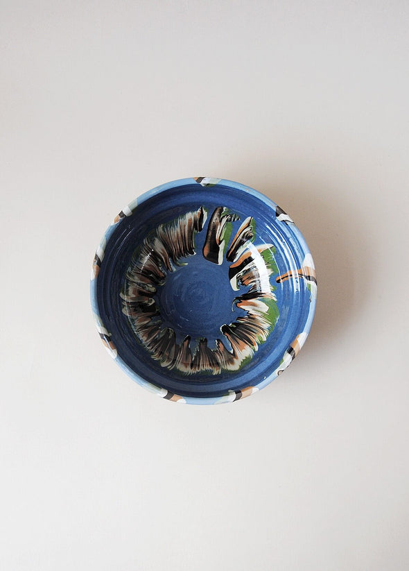 Ceramic bowl decorated in traditional Romanian pattern. Blue base with patterned glaze in orange, cream, green and black.