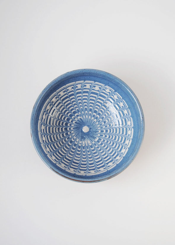 Ceramic bowl decorated in traditional Romanian pattern. Blue base with swirls of white.