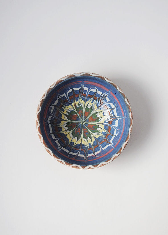 Ceramic bowl decorated in traditional Romanian pattern. Blue base with swirls of white, red, yellow, green and brown.