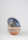 Stack of three ceramic bowls decorated in traditional Romanian pattern. Blue base with swirls of white, red, yellow, green and brown.