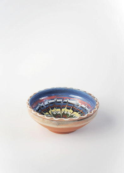 Ceramic bowl decorated in traditional Romanian pattern. Blue base with swirls of white, red, yellow, green and brown.