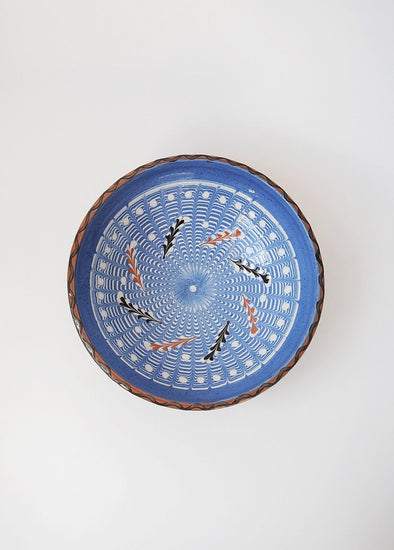 Ceramic bowl decorated in traditional Romanian pattern. Blue base with swirls of white and brown.