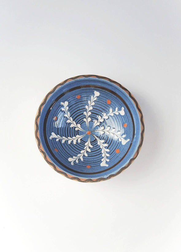 Ceramic bowl decorated in traditional Romanian pattern. Blue base with swirls of white and brown.