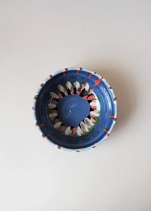 Ceramic bowl decorated in traditional Romanian pattern. Blue base with patterned glaze in red, cream, green and black.