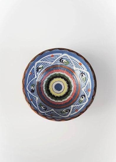 Ceramic bowl decorated in traditional Romanian pattern. Blue base with swirls of black, blue, green, white, red, brown and yellow.