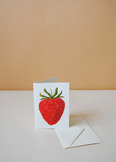 A greetings card with a painted image of a red strawberry.