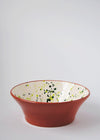 Ceramic salad bowl. White glaze with green splatter pattern on interior and terracotta glaze on exterior. 