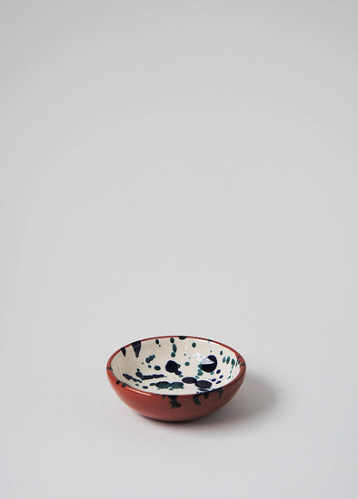 Ceramic small bowl. White glaze with blue splatter pattern on interior and terracotta glaze on exterior.