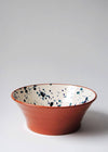 Ceramic salad bowl. White glaze with blue splatter pattern on interior and terracotta glaze on exterior.