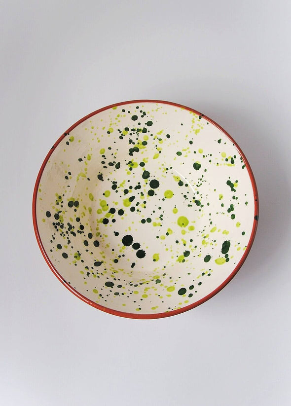 Ceramic salad bowl from above. White glaze with green splatter pattern on interior and terracotta glaze on exterior.