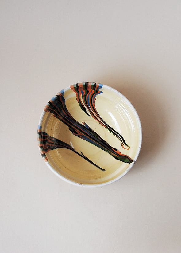 Ceramic bowl decorated in traditional Romanian pattern. Cream base with stripes of orange, green and blue across one side of the bowl.