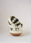 Stack of ceramic bowls decorated in traditional Romanian pattern. Cream base with stripes of orange, green and blue across one side of the bowl.