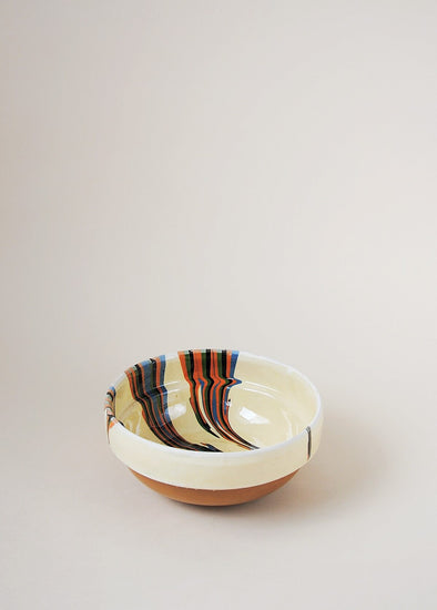 Ceramic bowl decorated in traditional Romanian pattern. Cream base with stripes of orange, green and blue across one side of the bowl.