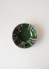 Ceramic bowl decorated in traditional Romanian pattern. Green base with patterned glaze in red, blue, yellow, cream and black.