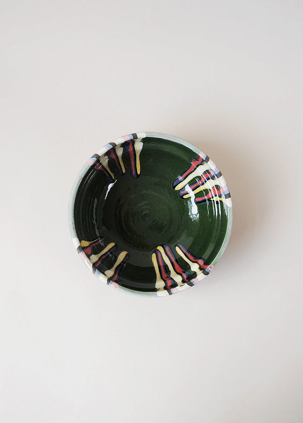 Ceramic bowl decorated in traditional Romanian pattern. Green base with patterned glaze in red, blue, yellow and black.