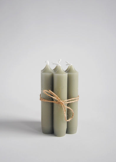 A group of seven light green short dinner candles tied together with twine.