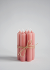 A group of seven short dinner candles tied with twine. They are a dusky pink colour.