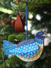 A blue dove decoration hanging from a Christmas tree. 