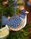 A blue dove decoration hanging from a Christmas tree. 