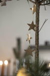 Close up of a garland of brass stars hanging down the top of a Christmas tree. 