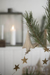 Close up of a garland of brass stars draped across a branch of a Christmas tree.