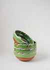 Stack of ceramic bowls decorated in traditional Romanian pattern. Green base with patterned glaze in orange, blue, yellow, cream and black.