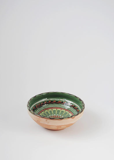 Ceramic bowl decorated in traditional Romanian pattern. Green base with swirls of white, yellow, black and brown.