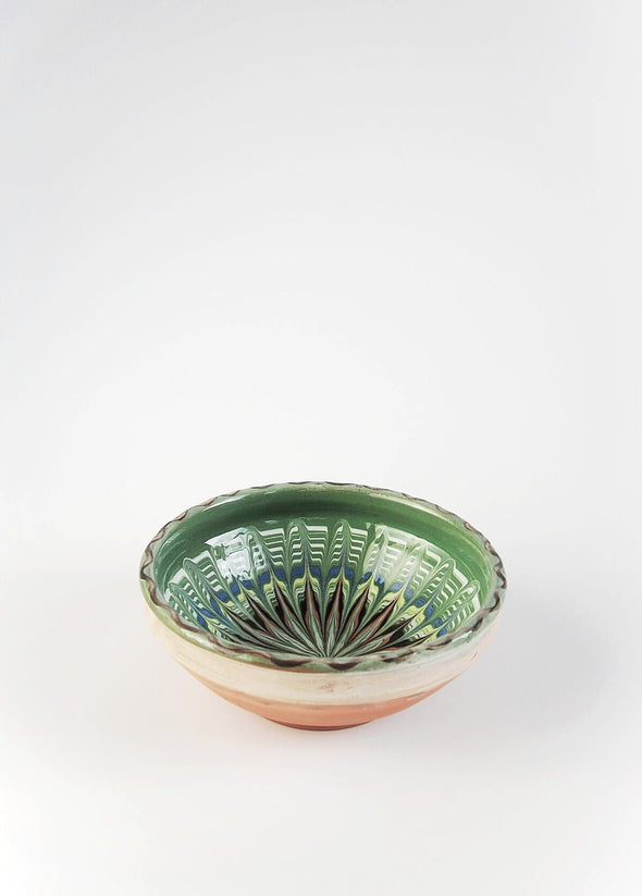 Ceramic bowl decorated in traditional Romanian pattern. Green base with swirls of black, blue, white, red and yellow.