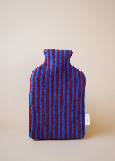 Knitted hot water bottle cover in blue and burgundy stripes.