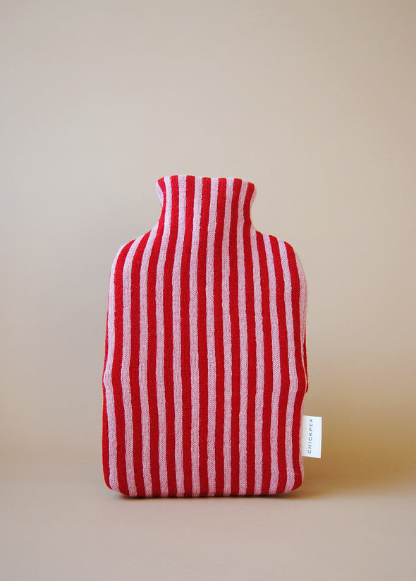 Knitted hot water bottle cover in red and pink stripes