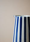 Close up of a blue and white striped ceramic jug.