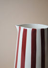 Close up of a burgundy and white striped ceramic jug.