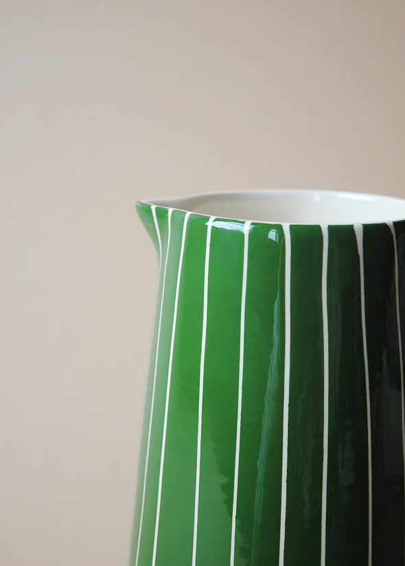 Close up of a green and white striped ceramic jug.