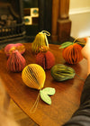 A group of paper fruit decorations resting on a wooden table.