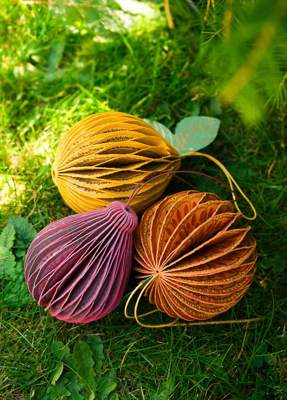 Three colourful decorative paper fruit decorations on grass