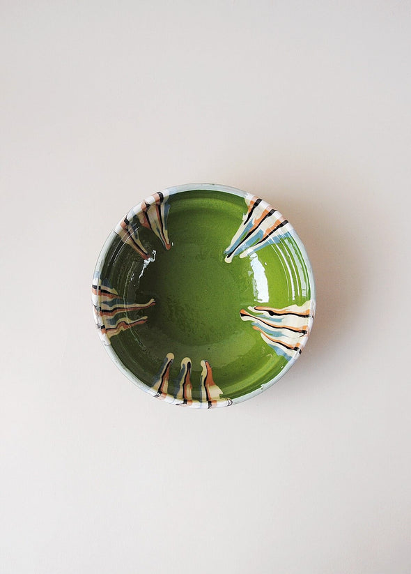 Ceramic bowl decorated in traditional Romanian pattern. Green base with patterned glaze in orange, blue,  cream and black.