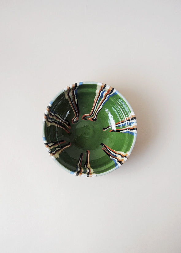 Ceramic bowl decorated in traditional Romanian pattern. Green base with patterned glaze in orange, blue, cream and black.