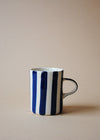 White ceramic mug with deep blue painted stripes.