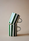 Two ceramic mugs in a stack. They are white with dark green painted stripes.