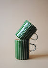 Two green and white striped ceramic mugs in a stack.