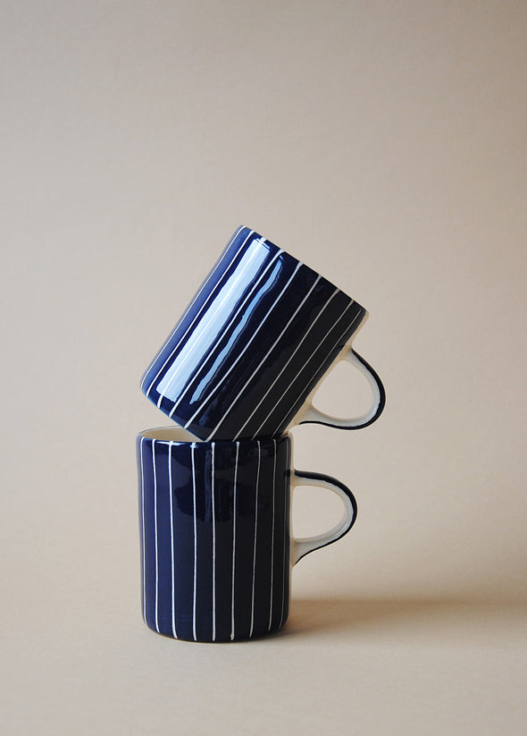 Two blue and white striped ceramic mugs in a stack.