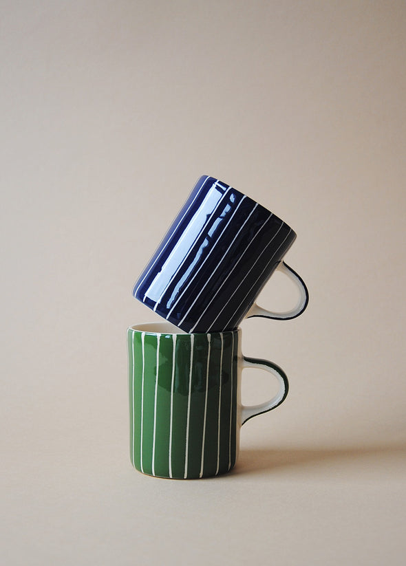 One blue and white striped ceramic mug and one green and white striped ceramic mug in a stack.