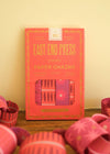 Red packet of East End Press paper chains on a wooden surface with pink paper chains around.