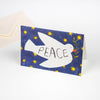 Greetings card featuring a dove against a starry deep blue sky. The dove is carrying an olive branch and has the word peace printed on its body.