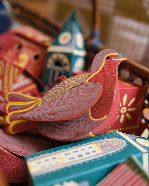 A box of decorations. On the top sits a red robin hanging decoration.