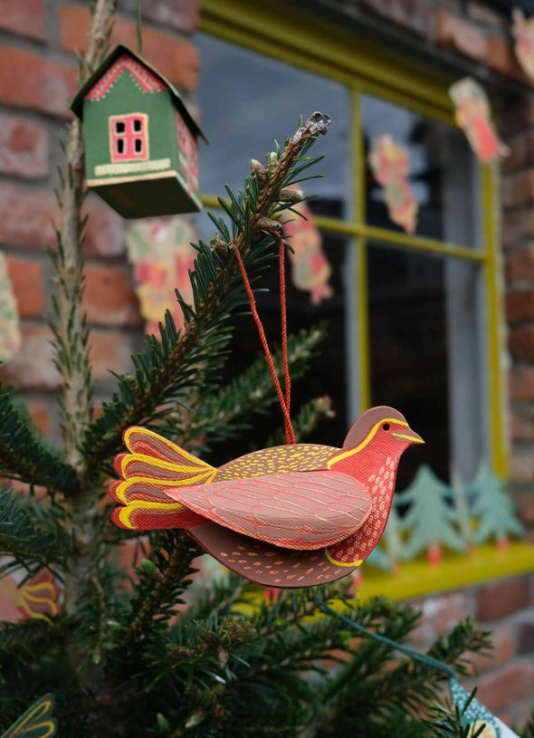 Red robin decoration hanging from a Christmas tree.