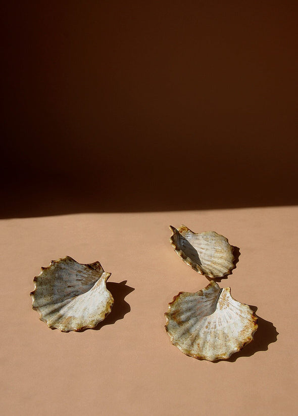Three ceramic scallop shells glazed in cream and light brown. 